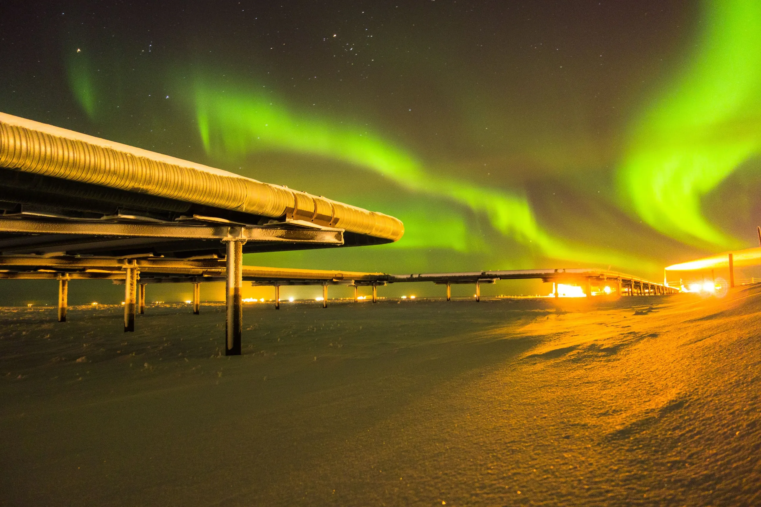 Elevated pipeline across snow under the northern lights